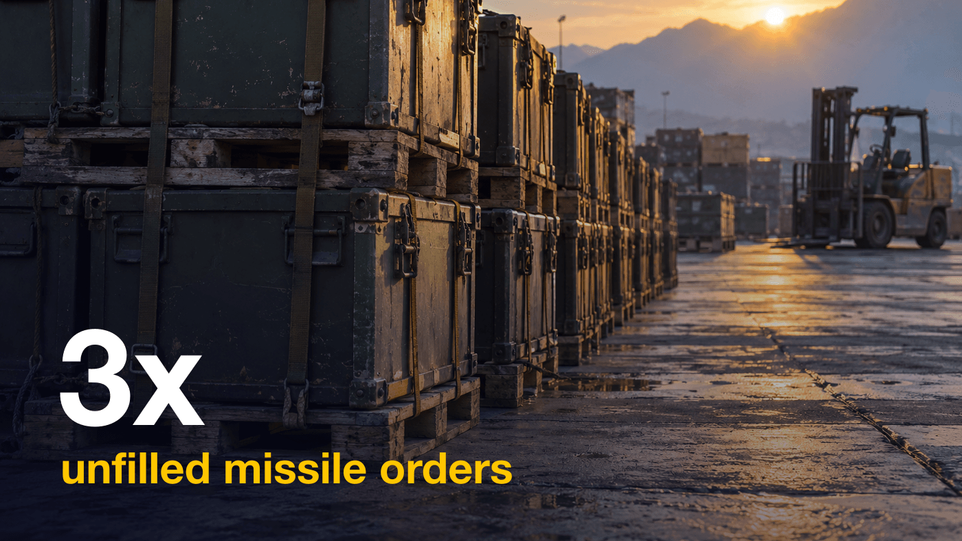 Long rows of olive drab military shipping cases strapped on wooden pallets on a depot apron at dawn, with a forklift in soft focus behind