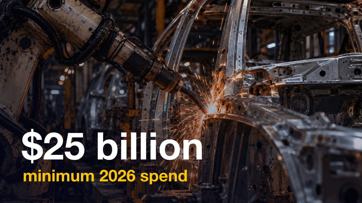 A welding robot sends sparks across an unpainted car body frame on a factory assembly line