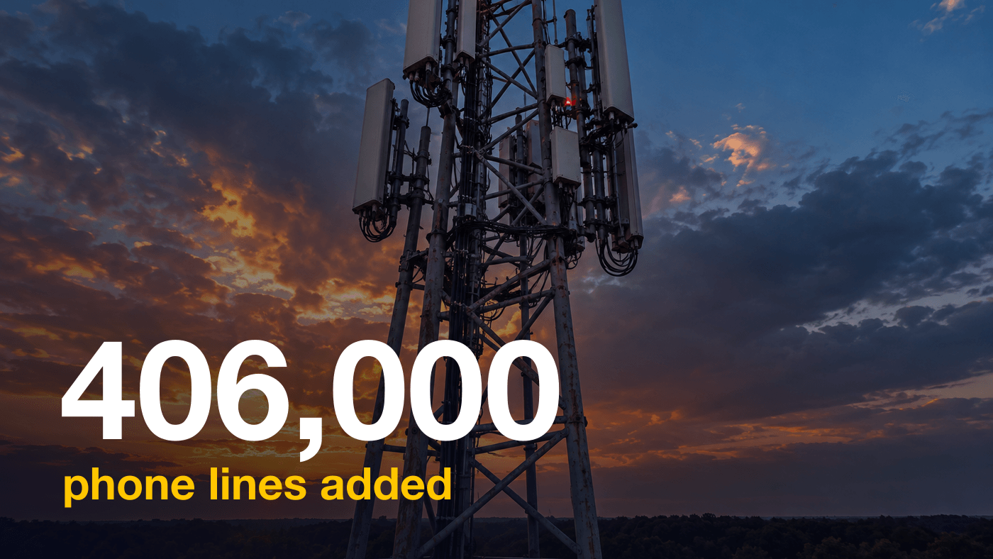 A steel cellphone tower with a cluster of antennas against an evening sky